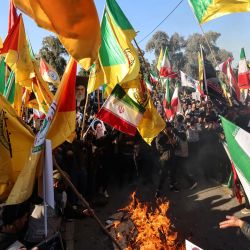 Manifestantes ondean banderas iraníes, junto con banderas de facciones armadas iraquíes leales a Irán, mientras queman banderas estadounidenses e israelíes durante una manifestación cerca de la embajada iraní en Bagdad, contra Israel y las recientes amenazas estadounidenses de acción militar en Irán, y en apoyo al régimen iraní y a su líder supremo. | Foto:AHMAD AL-RUBAYE / AFP