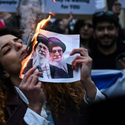 Un manifestante antirrégimen iraní enciende un cigarrillo con un papel encendido que representa a Ali Khamenei, líder supremo de Irán, durante una concentración frente al consulado estadounidense en Milán, Italia. | Foto:PIERO CRUCIATTI / AFP