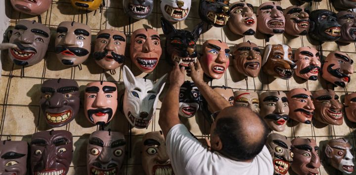Imagen del artesano Celio López acomodando máscaras típicas en su taller de máscaras utilizadas en danzas tradicionales, en el departamento de San Salvador, El Salvador.