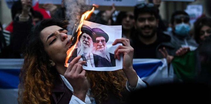 Un manifestante antirrégimen iraní enciende un cigarrillo con un papel encendido que representa a Ali Khamenei, líder supremo de Irán, durante una concentración frente al consulado estadounidense en Milán, Italia.