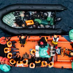 Esta fotografía aérea muestra a la tripulación del barco de rescate "Ocean Viking" rescatando una embarcación con migrantes en peligro utilizando una lancha neumática rígida (RHIB) en la zona de búsqueda y rescate frente a aguas internacionales de Libia. Cuarenta y seis migrantes fueron rescatados por la tripulación del "Ocean Viking" en aguas internacionales frente a la costa de Libia cuando intentaban llegar a la isla italiana de Lampedusa. Libia, situada a unos 300 km de la costa italiana, es uno de los principales puntos de salida del norte de África para migrantes, principalmente del África subsahariana, que arriesgan sus vidas al intentar cruzar el mar Mediterráneo. | Foto:SAMEER Al-DOUMY / AFP
