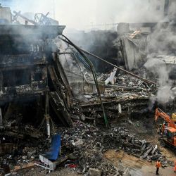 Los equipos de rescate buscan entre los escombros con excavadoras tras un gran incendio en un centro comercial de Karachi, Pakistán. | Foto:Asif Hassan / AFP