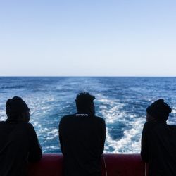 Migrantes en la cubierta de popa del barco de rescate "Ocean Viking", operado por la ONG SOS Mediterranee, mientras navega hacia una zona de socorro en aguas internacionales frente a la costa de Libia. | Foto:SAMEER Al-DOUMY / AFP