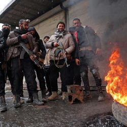 Tropas del gobierno sirio montan guardia junto a un neumático en llamas en una calle de Tabqa, en la provincia de Raqa, en la ribera suroeste del Éufrates. | Foto:OMAR HAJ KADOUR / AFP