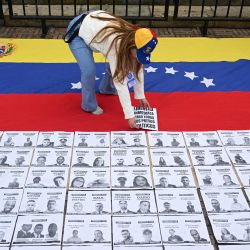 Una mujer coloca un cartel con la leyenda "Libertad inmediata a todos los presos políticos" sobre una bandera venezolana durante una manifestación en la Plaza Bolívar de Bogotá, Colombia. | Foto:Raúl Arboleda / AFP