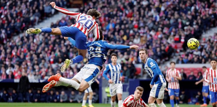 El delantero argentino del Atlético de Madrid, Giuliano Simeone, y el defensor español del Alavés, Víctor Parada, saltan por la pelota durante el partido de fútbol de la liga española entre el Club Atlético de Madrid y el Deportivo Alavés en el Estadio Metropolitano de Madrid.