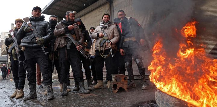 Tropas del gobierno sirio montan guardia junto a un neumático en llamas en una calle de Tabqa, en la provincia de Raqa, en la ribera suroeste del Éufrates.