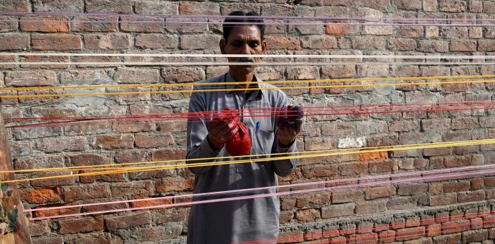 Un hombre aplica capas de polvo de vidrio a las cuerdas de una cometa antes del Festival de Basant en Lahore, Pakistán.