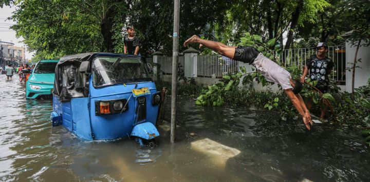 Un joven se sumerge en las aguas de la inundación después de que las fuertes lluvias dejaran zonas residenciales parcialmente sumergidas en Yakarta, Indonesia.