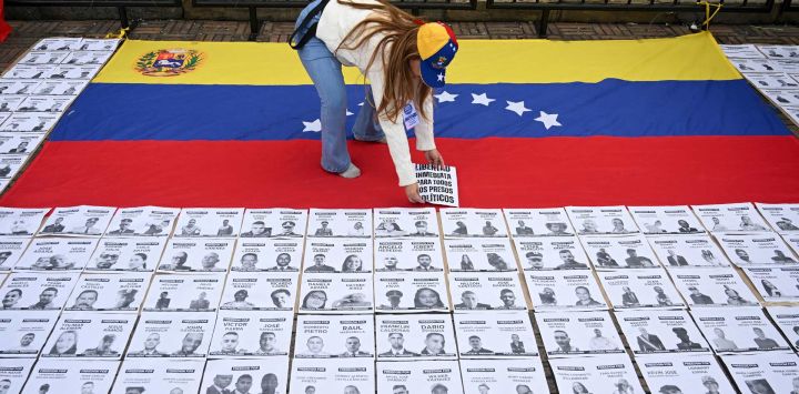 Una mujer coloca un cartel con la leyenda "Libertad inmediata a todos los presos políticos" sobre una bandera venezolana durante una manifestación en la Plaza Bolívar de Bogotá, Colombia.