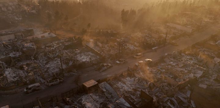 Vista aérea de los restos calcinados de viviendas destruidas al atardecer tras un incendio forestal en Concepción, Chile. Incendios forestales descontrolados arrasaron comunidades del sur de Chile, dejando ruinas calcinadas y al menos 19 muertos, informaron las autoridades.