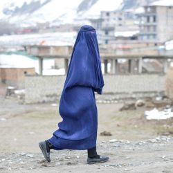 Una mujer afgana con burka camina por una calle con las montañas nevadas de fondo en el distrito de Argo, provincia de Badakhshan. | Foto:OMER ABRAR / AFP