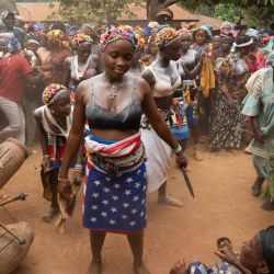 Niñas bailan rodeadas de una multitud en la aldea de Yagala, Sierra Leona. En comunidades de Sierra Leona, la sociedad Bondo organiza un poderoso rito de paso para las adolescentes, uniendo generaciones mediante vibrantes ceremonias que reafirman la identidad cultural. Como se muestra en estas fotografías de la aldea de Yagala, la iniciación comienza con una despedida comunitaria: una celebración dinámica de danza, tambores y bendiciones, donde los ancianos conducen a las niñas hacia el bosque para semanas de aislamiento e instrucción ancestral. Esta práctica, programada para no interrumpir la escuela ni las cosechas, representa una piedra angular de la vida social, marcando su transición a la edad adulta. | Foto:Gemma Bonfiglioli / AFP