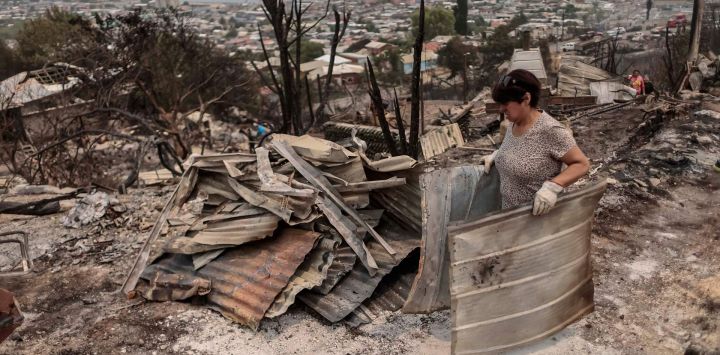 Personas realizan trabajos de limpieza de casas destruidas después de un incendio forestal, en la comuna de Penco, en la región del Biobío, Chile.