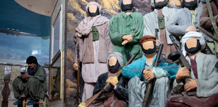Esta fotografía muestra a un visitante afgano sentado junto a un diorama con figuras de combatientes muyahidines, pintadas con yeso para censurar el Manzar-e-Jahad, o Museo de la Yihad, que conmemora la resistencia afgana a la invasión soviética de 1979, en Herat.