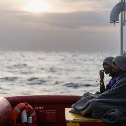 Migrantes bangladesíes sentados en la cubierta de popa del barco de rescate "Ocean Viking", operado por la ONG SOS Mediterranee, mientras navega por el mar Mediterráneo hacia el puerto de desembarco designado en Palermo, sur de Italia. | Foto:SAMEER Al-DOUMY / AFP