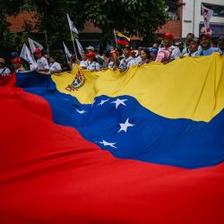 Partidarios del destituido presidente venezolano Nicolás Maduro sostienen una bandera nacional gigante durante una manifestación para exigir su liberación y la de su esposa de una prisión estadounidense en Caracas. Miles de simpatizantes de Nicolás Maduro marcharon en Caracas exigiendo la liberación del presidente destituido, coincidiendo con el 68.º aniversario de la caída de la dictadura militar en Venezuela. | Foto:JUAN BARRETO / AFP