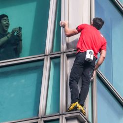 Un ocupante del edificio graba con su teléfono al escalador estadounidense Alex Honnold mientras escala el edificio Taipei 101 sin cuerdas ni equipo de seguridad en Taipéi, Taiwán. | Foto:I-Hwa Cheng / AFP