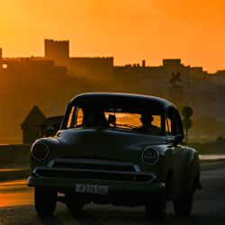 Un automóvil antiguo circula por el Malecón de La Habana al amanecer. | Foto:YAMIL LAGE / AFP