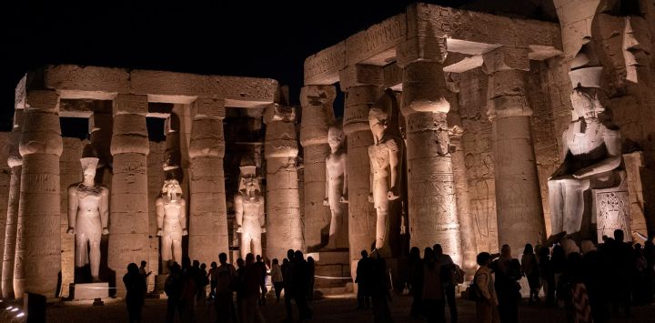 Imagen de turistas visitando el Templo de Luxor por la noche, en Luxor, Egipto.