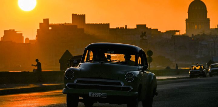 Un automóvil antiguo circula por el Malecón de La Habana al amanecer.