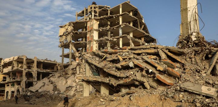 Palestinos caminan frente a edificios destruidos, en el barrio de Zeitoun, en el sureste de la Ciudad de Gaza.