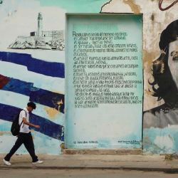 Imagen de dos jóvenes caminando frente a un muro pintado con el retrato del Che Guevara, en La Habana, Cuba. | Foto:Xinhua/Jiang Biao