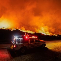 Bomberos viajan en un vehículo por una carretera junto a un incendio forestal en las montañas de la zona rural de Epuyén, en la región patagónica de la provincia de Chubut, Argentina. El gobierno argentino declaró emergencia en la Patagonia, donde los incendios forestales han arrasado vastas extensiones de bosque desde el inicio del verano austral. | Foto:GONZALO KEOGAN / AFP