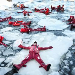Participantes con trajes isotérmicos flotan entre témpanos de hielo en un agujero en el río Moscova congelado, disfrutando de la creciente tendencia de relajación, en Moscú, Rusia. | Foto:Alexander Nemenov / AFP