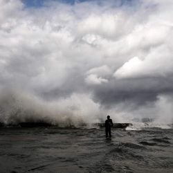 Un hombre se encuentra en el Malecón inundado mientras las olas rompen tras la llegada de un frente frío a La Habana, Cuba. | Foto:YAMIL LAGE / AFP