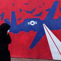 Una mujer pasa junto a un mural que representa un dron estadounidense, pintado en los muros exteriores de la antigua embajada estadounidense en Teherán, conocida popularmente como la "Guarida del Espionaje". El líder supremo de Irán, el ayatolá Alí Jamenei, advirtió de una "guerra regional" si Estados Unidos atacaba tras los intensos despliegues militares de Washington en el Golfo. | Foto:ATTA KENARE / AFP