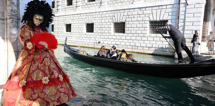 Imagen de un juerguista posando con una góndola cerca del Gran Canal durante el Carnaval de Venecia 2026, en Venecia, Italia.