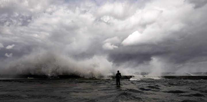 Un hombre se encuentra en el Malecón inundado mientras las olas rompen tras la llegada de un frente frío a La Habana, Cuba.