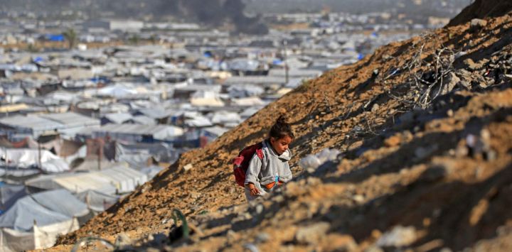 Una niña sube a la cima de una colina con el humo que se eleva desde el refugio de Gath, que alberga a palestinos desplazados, tras un ataque aéreo israelí al oeste de Khan Yunis, al sur de la Franja de Gaza. Los ataques aéreos israelíes mataron a 11 personas en la Franja de Gaza, según el Ministerio de Salud del territorio, incluidas personas refugiadas en una tienda de campaña en el sur.
