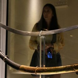 Una mujer observa el sable curvo que perteneció al héroe nacional argentino, el general José de San Martín, en el Museo Histórico Nacional de Buenos Aires. La decisión del gobierno de Javier Milei de trasladar el sable del Libertador argentino José de San Martín a un regimiento militar provocó la indignación de los herederos de la pieza, quienes exigieron judicialmente que el arma permaneciera en el Museo Histórico Nacional, donde fue donada en 1897. | Foto:LUIS ROBAYO / AFP