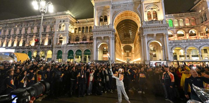 La bailarina italiana Nicoletta Manni (centro) lleva la llama olímpica a su llegada a la Piazza Duomo antes de la inauguración de los Juegos Olímpicos de Invierno Milano Cortina 2026 en Milán, Italia.