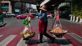 Un vendedor de cacahuetes cruza una carretera en Bangkok. Foto de Anthony WALLACE / AFP