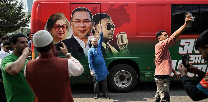 Seguidores del Partido Nacionalista de Bangladesh posan junto a un autobús a prueba de balas del presidente del BNP y candidato electoral Tarique Rahman. Foto de Sajjad HUSSAIN / AFP