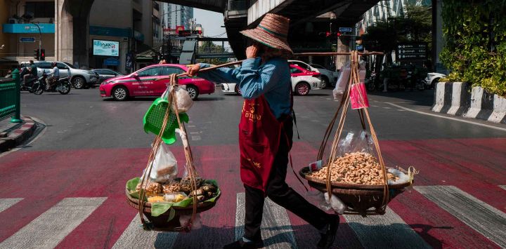 Un vendedor de cacahuetes cruza una carretera en Bangkok. Foto de Anthony WALLACE / AFP