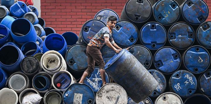 Un trabajador apila tambores vacíos fuera de una tienda en un mercado antes de las elecciones generales de Bangladesh en Dhaka. Foto de Sajjad HUSSAIN / AFP