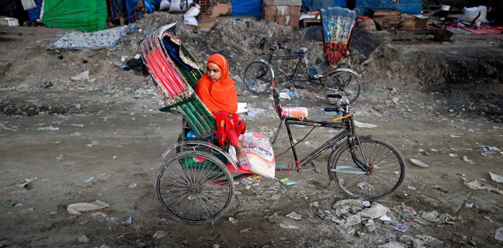 Una niña espera en un rickshaw cerca de un mercado en Dhaka. Foto de Sajjad HUSSAIN / AFP