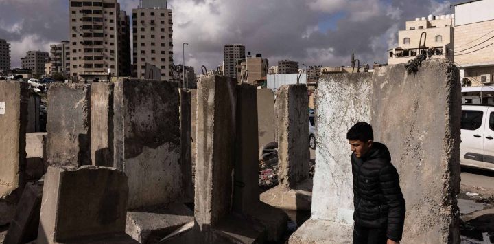 Un hombre palestino pasa junto a bloques de hormigón en el puesto de control de Qalandiya, controlado por Israel, en Cisjordania. Foto de JOHN WESSELS / AFP