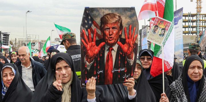 Mujeres marchan con un cartel que muestra al presidente estadounidense Donald Trump con las manos ensangrentadas en Teherán. Foto de AFP