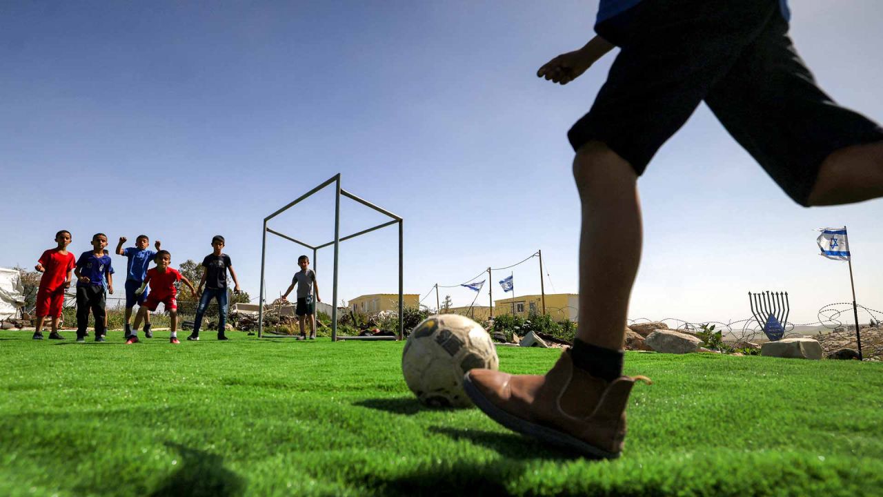 Niños palestinos juegan al fútbol en un campo rodeado de banderas israelíes, después de que el campo recibiera un aviso de demolición por parte de las autoridades israelíes.Foto de HAZEM BADER / AFP | Foto:AFP