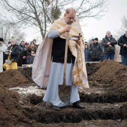 Un sacerdote ucraniano arroja puñados de tierra sobre los ataúdes durante una ceremonia funeraria. Foto de Ivan SAMOILOV / AFP | Foto:AFP