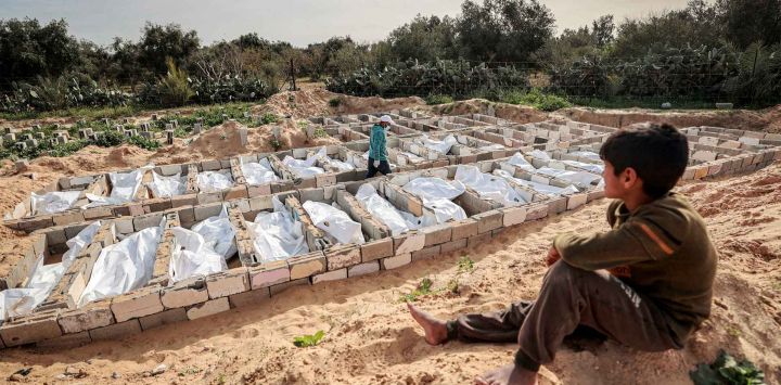 Un joven palestino observa cómo 53 cuerpos no identificados son enterrados en un cementerio de Deir el-Balah, en el centro de la Franja de Gaza. Foto de EYAD BABA / AFP