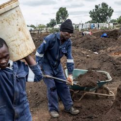 Un hombre lleva un balde mientras mineros artesanales que cavan hoyos buscan oro en un terreno fuera de Springs, Ekurhuleni. Foto de MARCO LONGARI / AFP | Foto:AFP