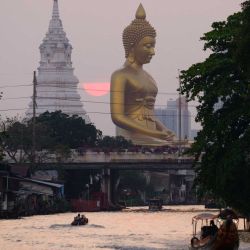 La gente navega en botes por un canal mientras el sol se pone detrás de la estatua gigante de Buda en Bangkok. Foto de Anthony WALLACE / AFP | Foto:AFP
