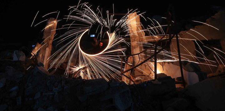 Palestinos desplazados encienden fuegos artificiales para celebrar el anuncio del inicio del mes sagrado musulmán de Ramadán, en el campo de refugiados de Bureij. Foto de Eyad Baba / AFP