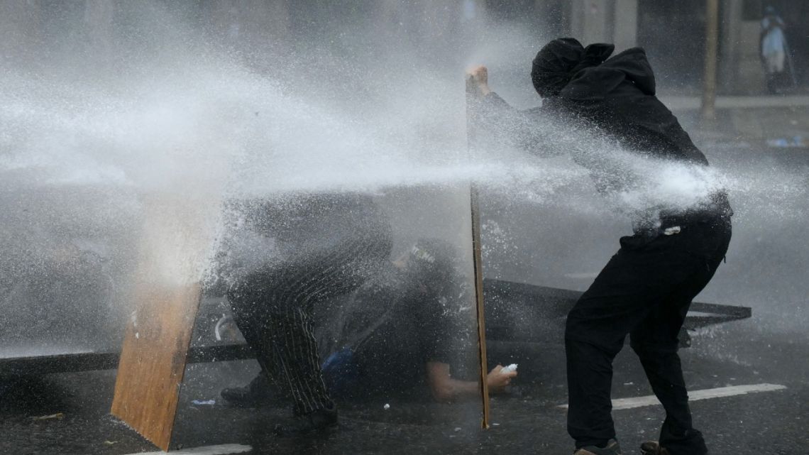 Demonstrators are hit by a water cannon fired by riot police during a protest called by trade unionists against the labor reform debate taking place in the National Congress in Buenos Aires on February 11, 2026.